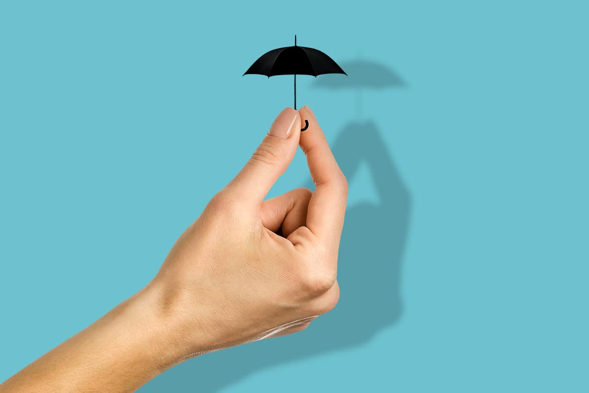 An illustration by Mariaelena Caputi showing a hand holding a small umbrella, a metaphor for the government's planned cuts to the welfare system with the risk of exposing the most vulnerable people.